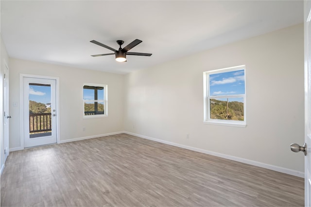 unfurnished room with light wood-style flooring, a wealth of natural light, and baseboards