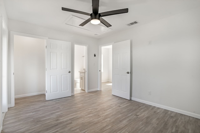 unfurnished bedroom featuring baseboards, attic access, visible vents, and wood finished floors