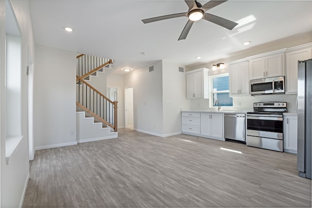 kitchen with light wood finished floors, stainless steel appliances, a sink, and light countertops