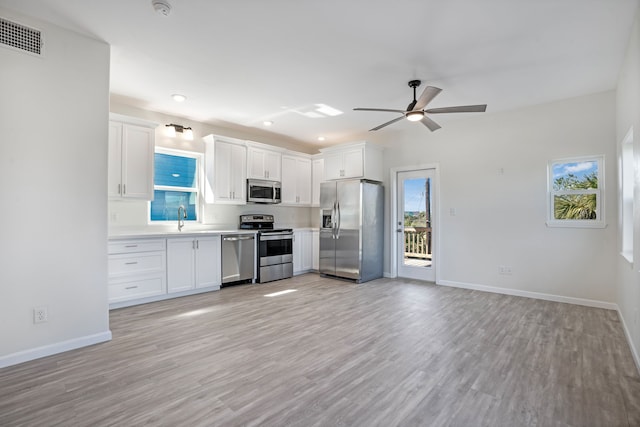 kitchen with visible vents, light wood-style flooring, stainless steel appliances, white cabinetry, and a sink