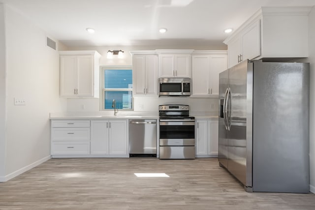 kitchen with a sink, visible vents, white cabinetry, light countertops, and appliances with stainless steel finishes