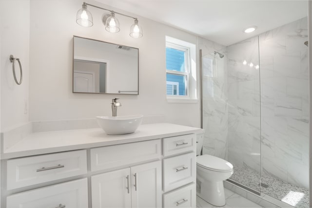 bathroom featuring toilet, marble finish floor, a marble finish shower, and vanity