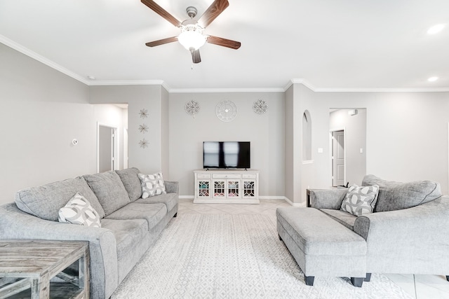 tiled living area featuring arched walkways, crown molding, baseboards, and ceiling fan