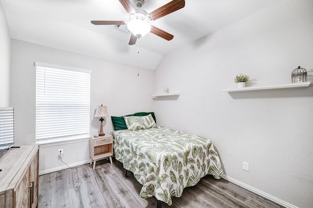 bedroom with vaulted ceiling, wood finished floors, and baseboards