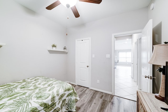 bedroom with light wood-style floors, ceiling fan, and baseboards