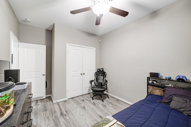 bedroom featuring baseboards, ceiling fan, a closet, and light wood-style floors