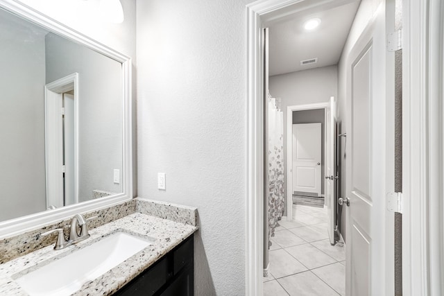 bathroom featuring a shower with curtain, visible vents, a textured wall, vanity, and tile patterned flooring