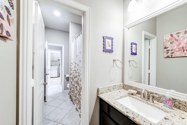 bathroom featuring washer / clothes dryer, vanity, toilet, and tile patterned floors