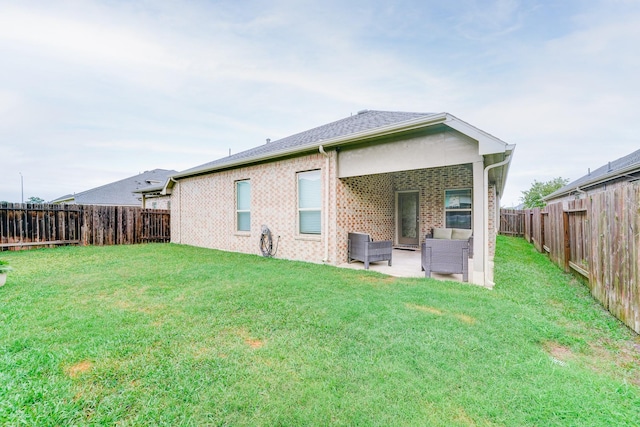 rear view of property with a fenced backyard, a yard, brick siding, and a patio