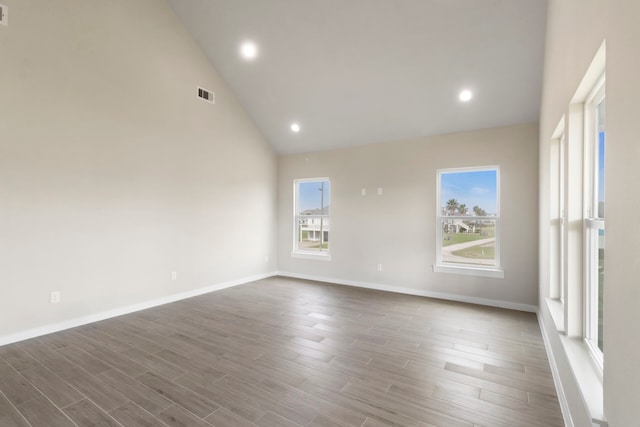 unfurnished room featuring high vaulted ceiling, visible vents, baseboards, and wood finished floors