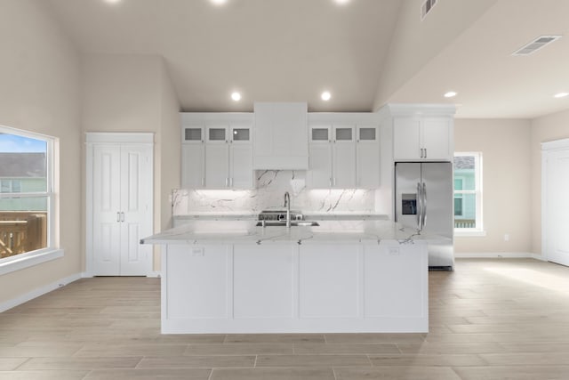 kitchen with stainless steel refrigerator with ice dispenser, a sink, visible vents, and white cabinetry