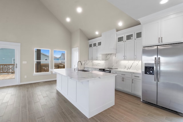 kitchen featuring stainless steel appliances, wood finish floors, a sink, custom exhaust hood, and backsplash