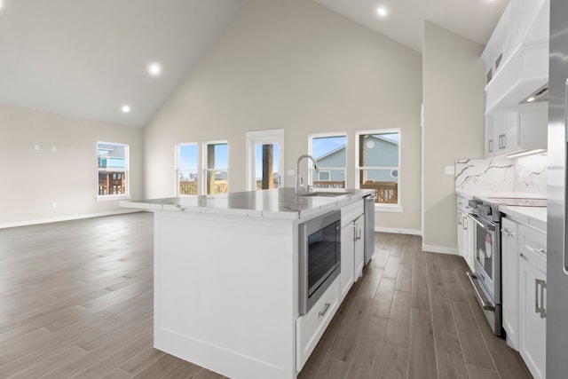 kitchen featuring stainless steel appliances, wood finished floors, a sink, white cabinetry, and an island with sink