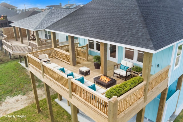 exterior space with a shingled roof, a deck, and an outdoor living space with a fire pit