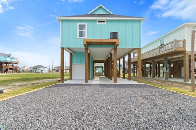 view of front facade featuring driveway, a shingled roof, a carport, stairs, and board and batten siding