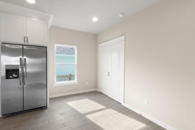 kitchen with light wood finished floors, baseboards, white cabinetry, stainless steel refrigerator with ice dispenser, and recessed lighting