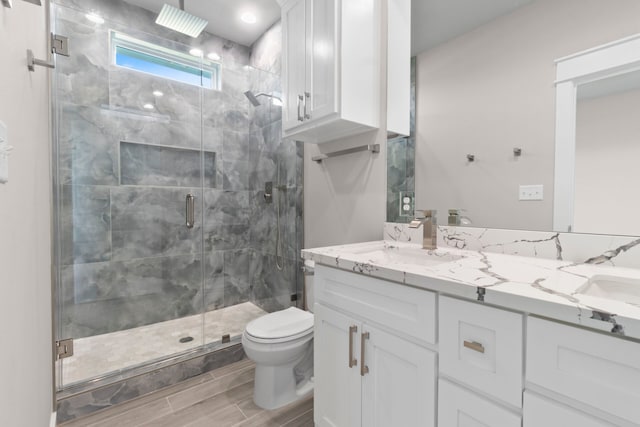 full bathroom with double vanity, a stall shower, a sink, and toilet