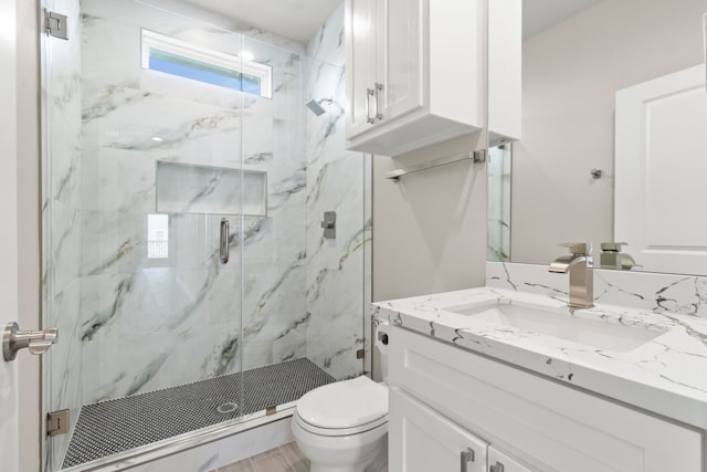 full bathroom featuring toilet, a marble finish shower, and vanity