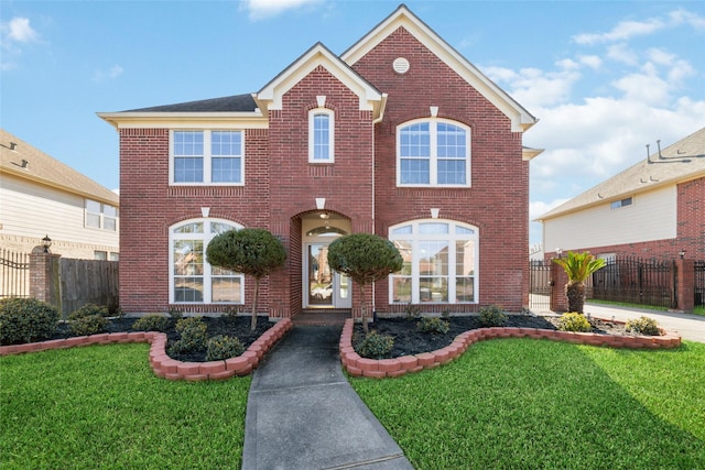 view of front facade featuring brick siding, a front lawn, and fence