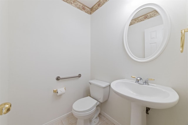 half bathroom with toilet, baseboards, and tile patterned floors