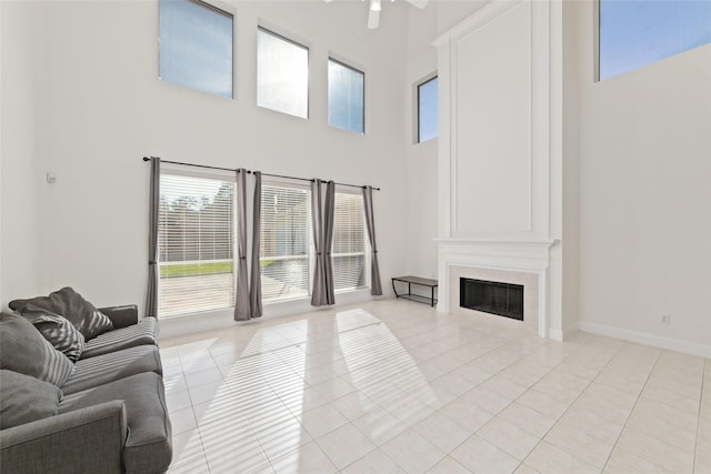 living area featuring light tile patterned floors, ceiling fan, a fireplace, and a healthy amount of sunlight