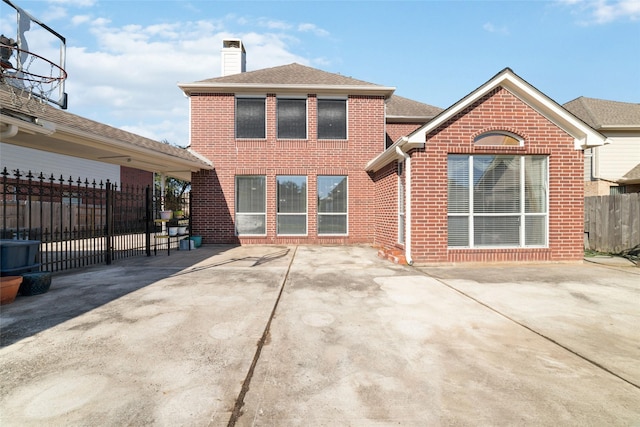 back of property featuring a patio area, a chimney, brick siding, roof with shingles, and fence