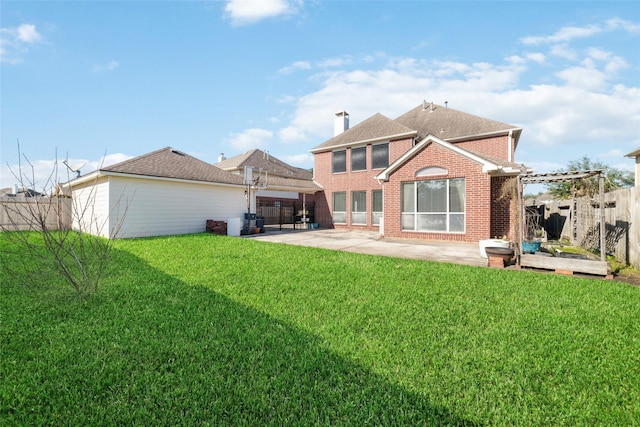 back of property with a fenced backyard, brick siding, a yard, a chimney, and a patio area