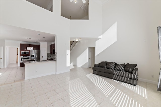 living room with light tile patterned floors, crown molding, a high ceiling, and stairs