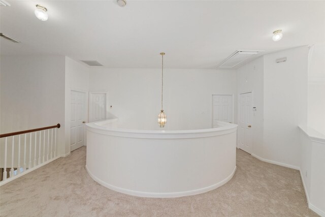 corridor with attic access, visible vents, light carpet, and baseboards
