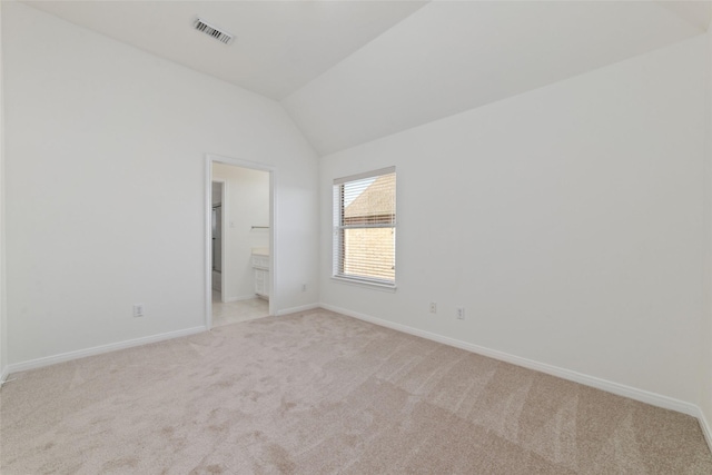 empty room with light colored carpet, visible vents, vaulted ceiling, and baseboards