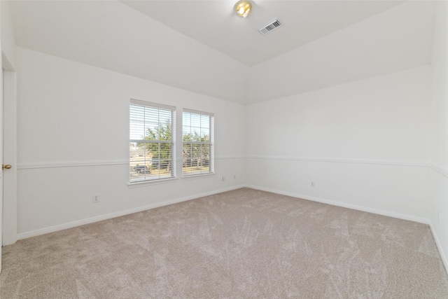 carpeted empty room featuring baseboards, visible vents, and vaulted ceiling