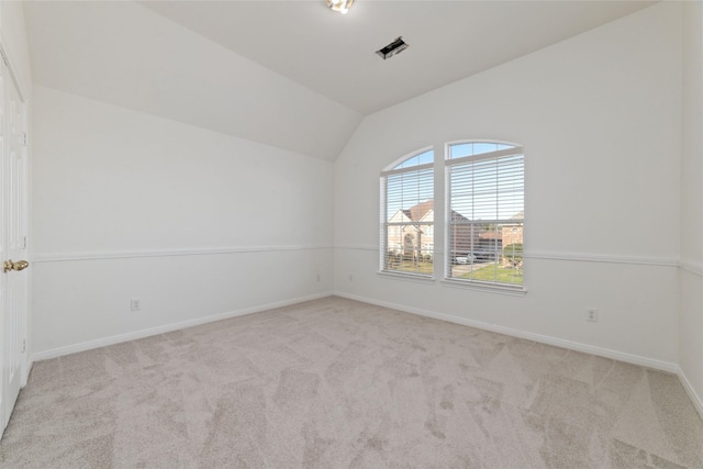 carpeted empty room featuring visible vents, baseboards, and vaulted ceiling