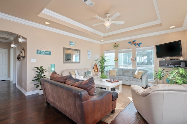 living area featuring visible vents, arched walkways, a raised ceiling, dark wood-style flooring, and crown molding