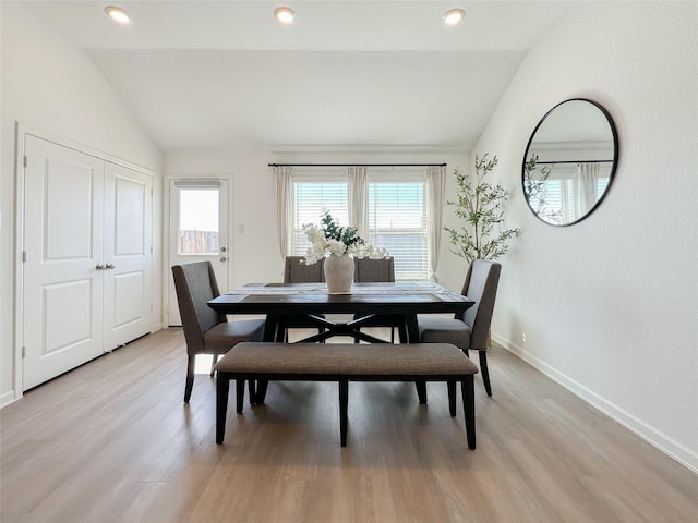 dining area featuring light wood-style flooring, baseboards, vaulted ceiling, and a wealth of natural light