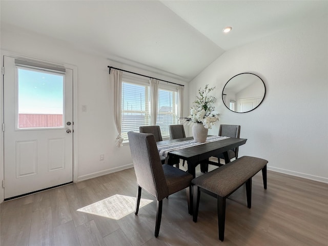 dining area featuring vaulted ceiling, light wood-style flooring, and baseboards