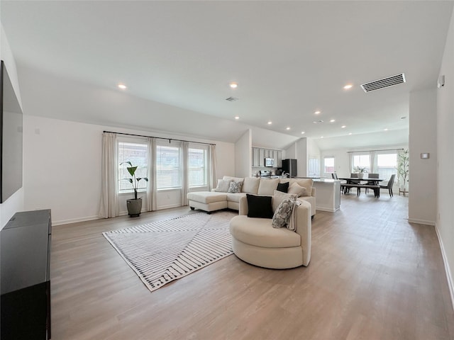 living area with light wood-style flooring, recessed lighting, visible vents, baseboards, and vaulted ceiling