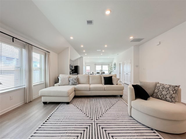 living area featuring lofted ceiling, recessed lighting, visible vents, light wood-type flooring, and baseboards