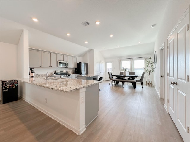 kitchen featuring stainless steel appliances, lofted ceiling, visible vents, light wood-style flooring, and a sink