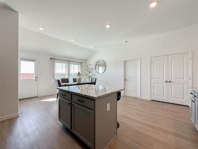 kitchen with lofted ceiling, gray cabinets, light wood-style flooring, and a center island