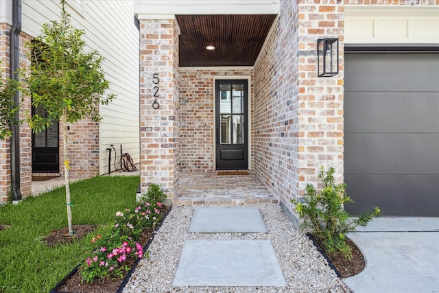 entrance to property with an attached garage and brick siding