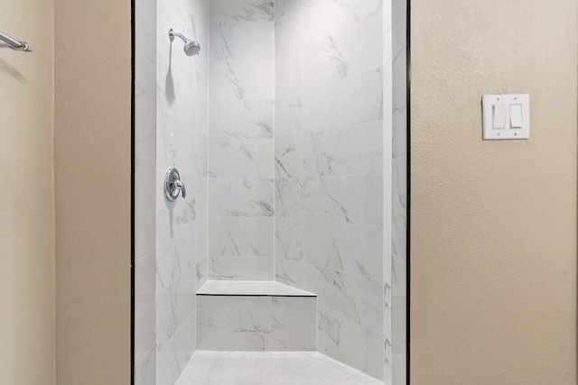 bathroom featuring a textured wall and walk in shower