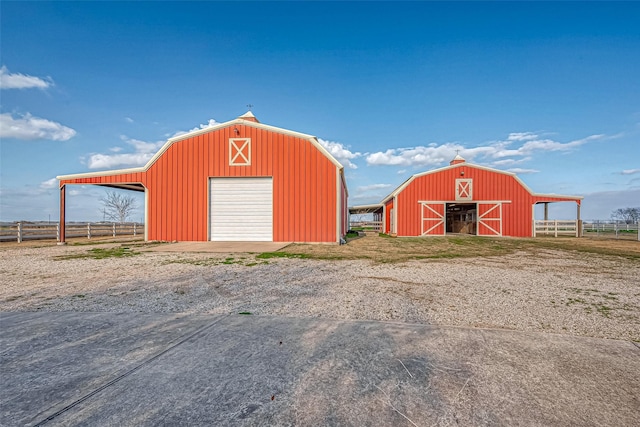 view of barn with driveway and fence