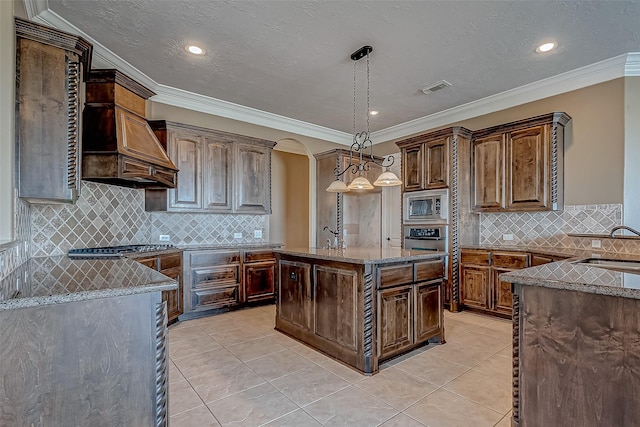 kitchen with light tile patterned floors, visible vents, appliances with stainless steel finishes, decorative light fixtures, and stone counters