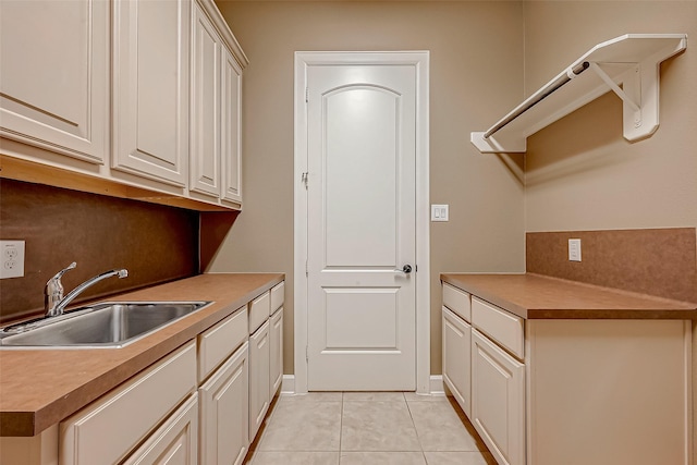 kitchen featuring light tile patterned floors, a sink, white cabinetry, baseboards, and tasteful backsplash