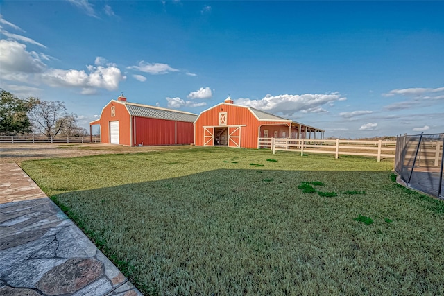 view of yard with a barn, a detached garage, fence, and an outdoor structure