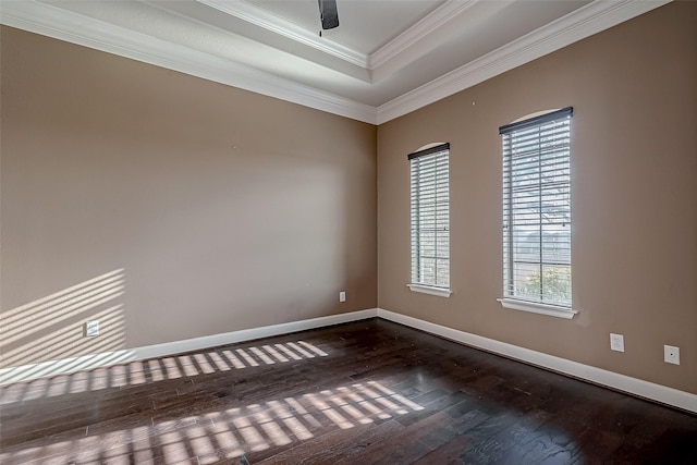 unfurnished room with ceiling fan, baseboards, a tray ceiling, dark wood finished floors, and crown molding
