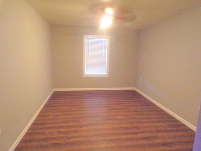 spare room with dark wood-type flooring, ceiling fan, and baseboards