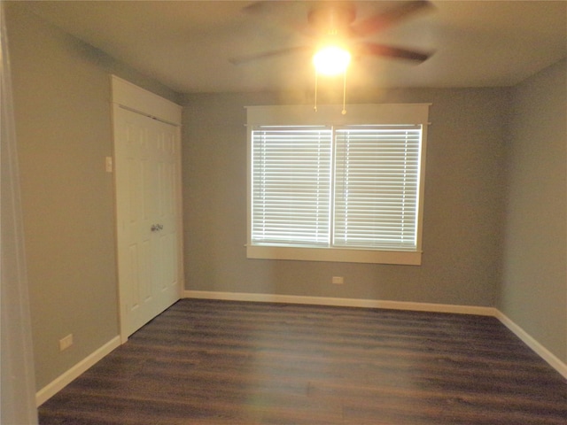 unfurnished room with baseboards, dark wood finished floors, and a ceiling fan