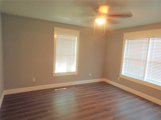 spare room featuring a ceiling fan, baseboards, and dark wood-style flooring