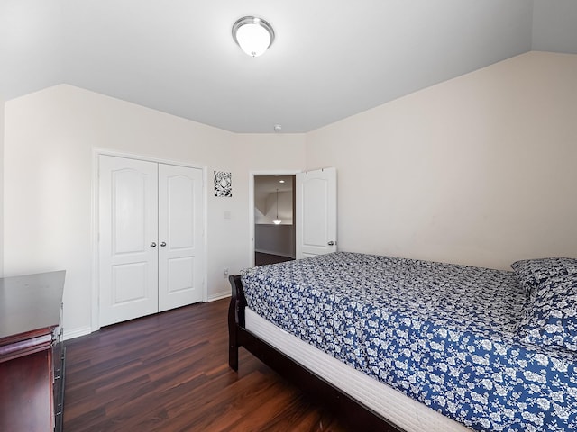 bedroom with lofted ceiling, dark wood-style flooring, a closet, and baseboards